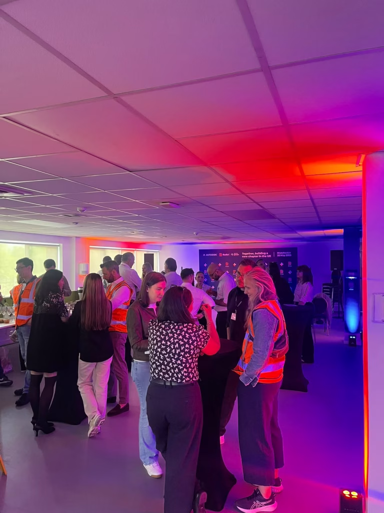 Guests networking at a corporate event with pink and purple ambient lighting